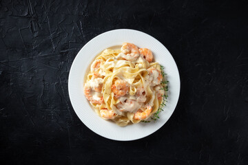 Seafood pasta. Pappardelle with shrimps and cream sauce, shot from the top with fresh thyme on a dark background