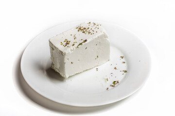 traditional white Greek feta and oregano cheese on a white plate on a white background