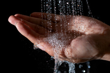 Fototapeta premium jets of water pouring into the palm on a black background
