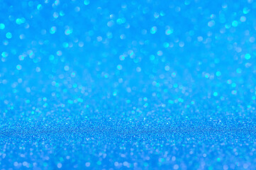 Blue bokeh glitters background. Abstract shiny backdrop. Blue design overlay with sparkling glimmers. Festive glittering sparks with blur effect. Selective focus