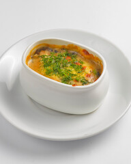 Roasted vegetables, potatoes, mushrooms and cheese in a pot. Baked dinner in a white pot. Delicious meal for dinner.