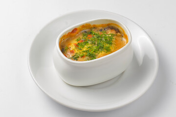 Roasted vegetables, potatoes, mushrooms and cheese in a pot. Baked dinner in a white pot. Delicious meal for dinner.