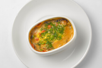 Roasted vegetables, potatoes, mushrooms and cheese in a pot. Baked dinner in a white pot. Delicious meal for dinner.