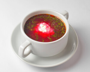 Ukrainian beetroot soup - borscht with sour cream served in a white bowl over white background.