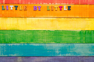 lgbt rainbow colors wooden background with inscription little by little