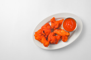Buffalo chicken wings with tomato dip sauce. Served on a white plate over white background.