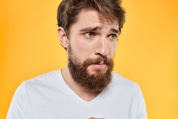 Fototapeta premium Man with emotional expression white t-shirt close-up studio yellow background
