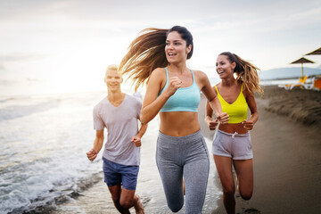 Group of young friends running and exercising on the beach