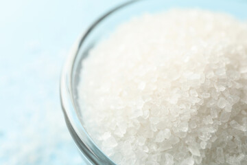 Glass bowl of salt on blue background