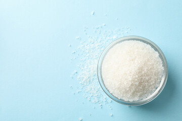 Glass bowl of salt on blue background