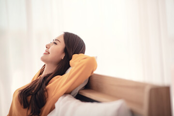 Relaxed young asian woman enjoying rest on comfortable bed, calm attractive girl relaxing and breathing fresh air in home, copy space.