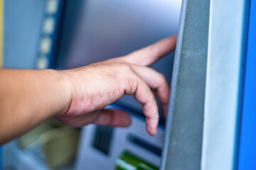 Close-up of man (wearing blue jean), using credit card to withdrawing money from ATM machine. Finance and business concept