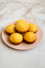 Homemade Cornbread Muffins on a pink plate, side view.