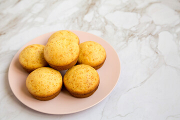 Homemade Cornbread Muffins on a pink plate, side view. Copy space.