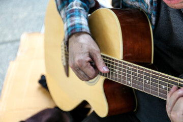Senoir man sitting and playing acoustic guitar.
