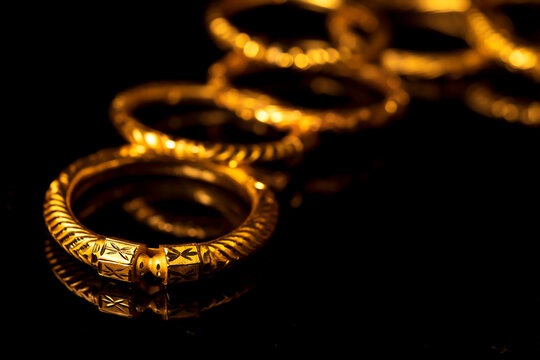 Traditional Indian Gold Jewelry. Expensive Gold bangle Jewelery on black background for diwali, dhanteras celebration shopping, gifting offer. Closeup of gold ornaments for festive occasion.