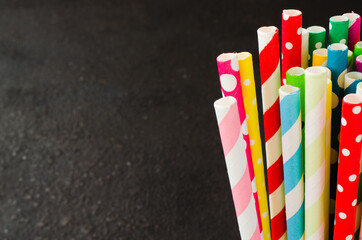 Fototapeta na wymiar Colorful paper straws of different colors for cocktails and drinks on dark background.