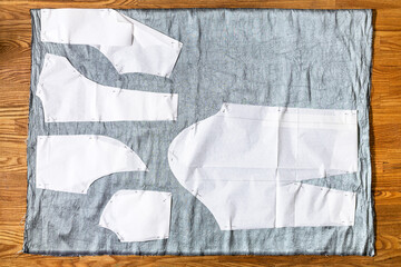top view of paper sewing pattern layouts of dress on gray fabric on wooden table at home