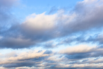 low gray and white clouds in blue sky in autumn twilight