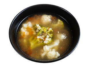 soup with stelline (italian pasta) and vegetables (cauliflower, broccoli, etc) in black bowl isolated on white background