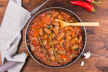 Traditional country Texas cowboy dish, beef sausages with beans, onions in tomato sauce in a frying pan, top view