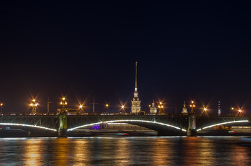 Fototapeta na wymiar Illuminated bridge over the river at night. Blurry background photo. View of Saint Petersburg.