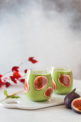 Matcha green vegan smoothie with chia seeds and figs in glasses on white background. Autumn detox recipe, superfoods, healthy eating. Japanese green matcha tea. Side view, copy space