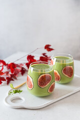 Matcha green vegan smoothie with chia seeds and figs in glasses on light background. Clean eating, alkaline diet, weight loss food concept. Superfood, detox. Side view, copy space