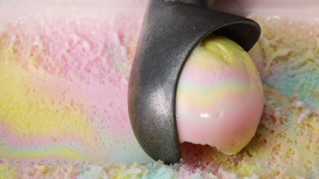 Slow motion Close up Stainless steel ice cream scoop is scooping rainbow flavor ice cream meat.
