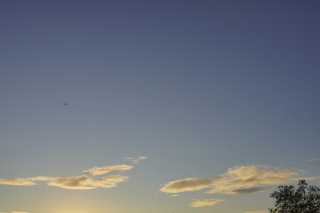 The sky of shortly autumn sunset on slight dark blue sky background.