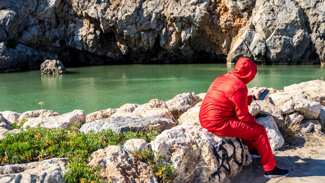 Man In A Red Jumpsuit And With A Black Backpack On A Beach