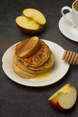 breakfast of coffee and apple pancakes with honey on a gray background.