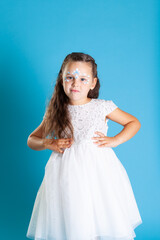 Fototapeta na wymiar portrait of a girl in a white Princess dress and snow Queen makeup with her hands on her waist isolated on a blue background.