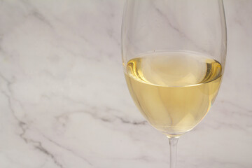 white wine in a glass on a marble background close up.