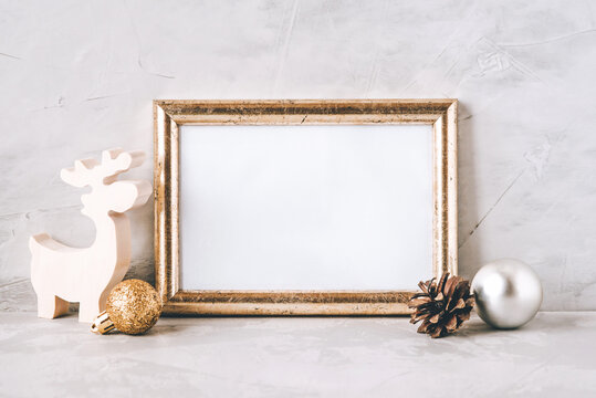 Golden photo frame and christmas decorations on gray background. Christmas, winter, new year concept. Copy space for text.