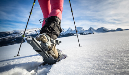 Young woman snowshoeing in high mountains, enjoying a lovely day