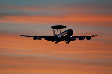 Avión militar AWACS aterrizando al anochecer