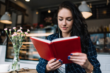 Pensive woman reading book in cafe