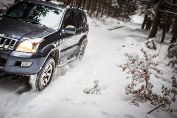 Motion blurred image of a big suv car going fast on a snow covered forest road