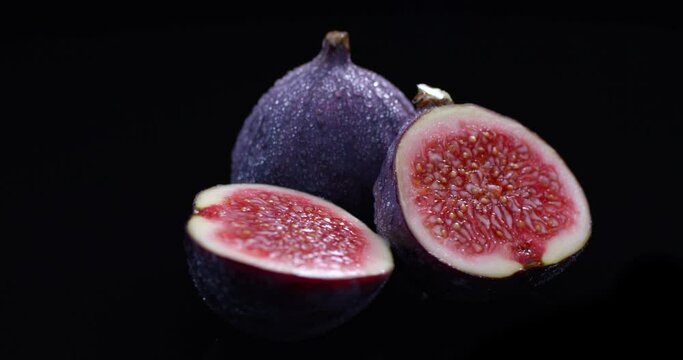 Fresh figs with water drops isolated on black background rotating