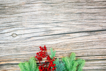 spruce branch with berries spruce branches and red beads on a string scattered on a wooden background from below top view with space for text or inscription