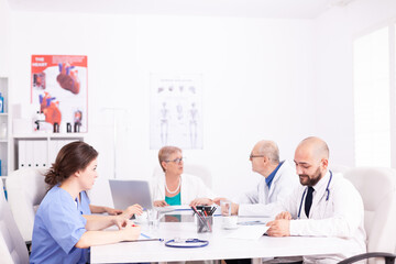 Fototapeta premium Medical team interacting at a meeting in conference room during discussion about health. Clinic expert therapist talking with colleagues about disease, medicine professional