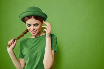 Happy woman with shamrock on St. Patrick's Day in green clothes and a hat on her head gesturing with her hands