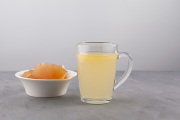 Liquid and congealed jelly-like homemade beef bone broth with natural collagen in mug on a gray background. Selective focus, copy space
