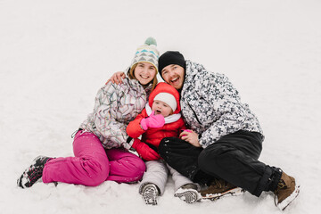 Fototapeta na wymiar Portrait of happy family walking in a snow winter park. Father, mother and children daughter are having fun and playing on snowy winter walk in nature.
