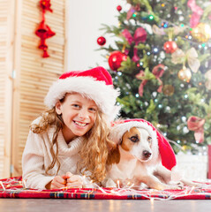 Child with dog near christmas tree