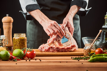 Chef brushing raw beef ribs with marinade