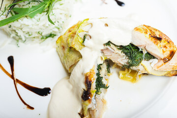 Fillet of white fish sea bass, cod stuffed with greens and rice on the table in the restaurant.