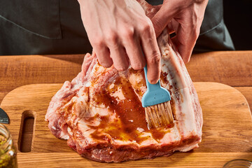 Man brushing raw beef meat with marinade