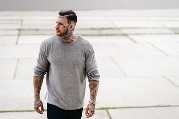 Portrait eines jungen muskulösen Mannes mit Tattoos, Sweater Shirt. Lifestyle Mode Influencer